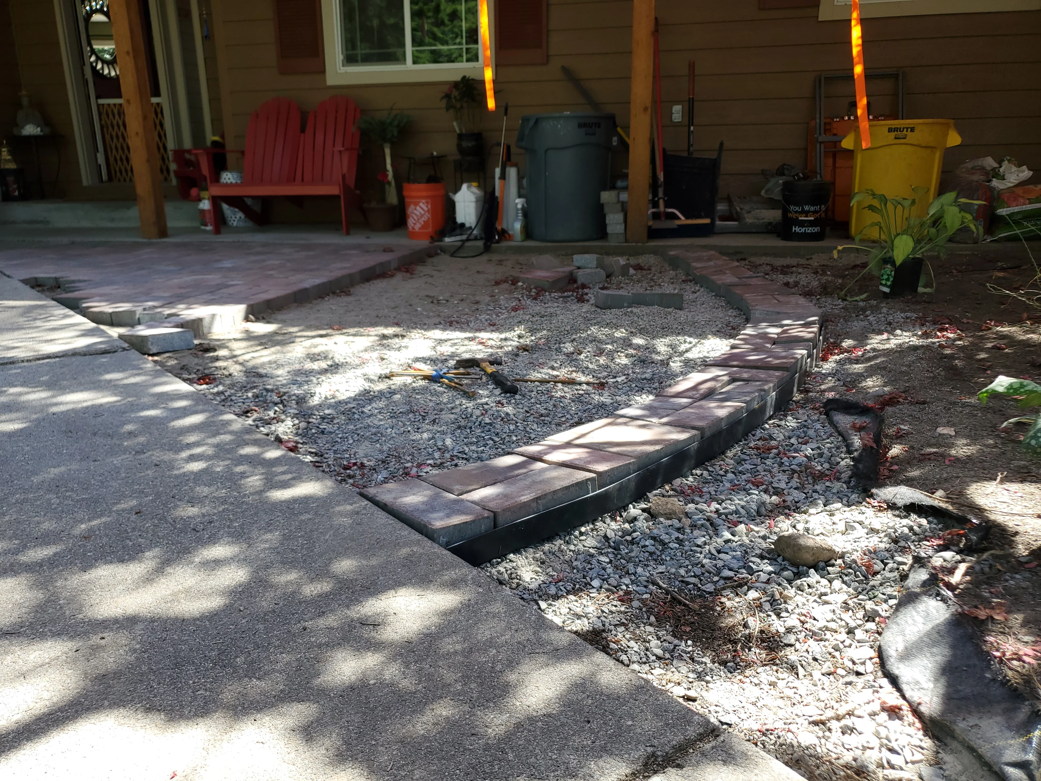 Curved concrete paver patio with gravel infill and stone edging under construction