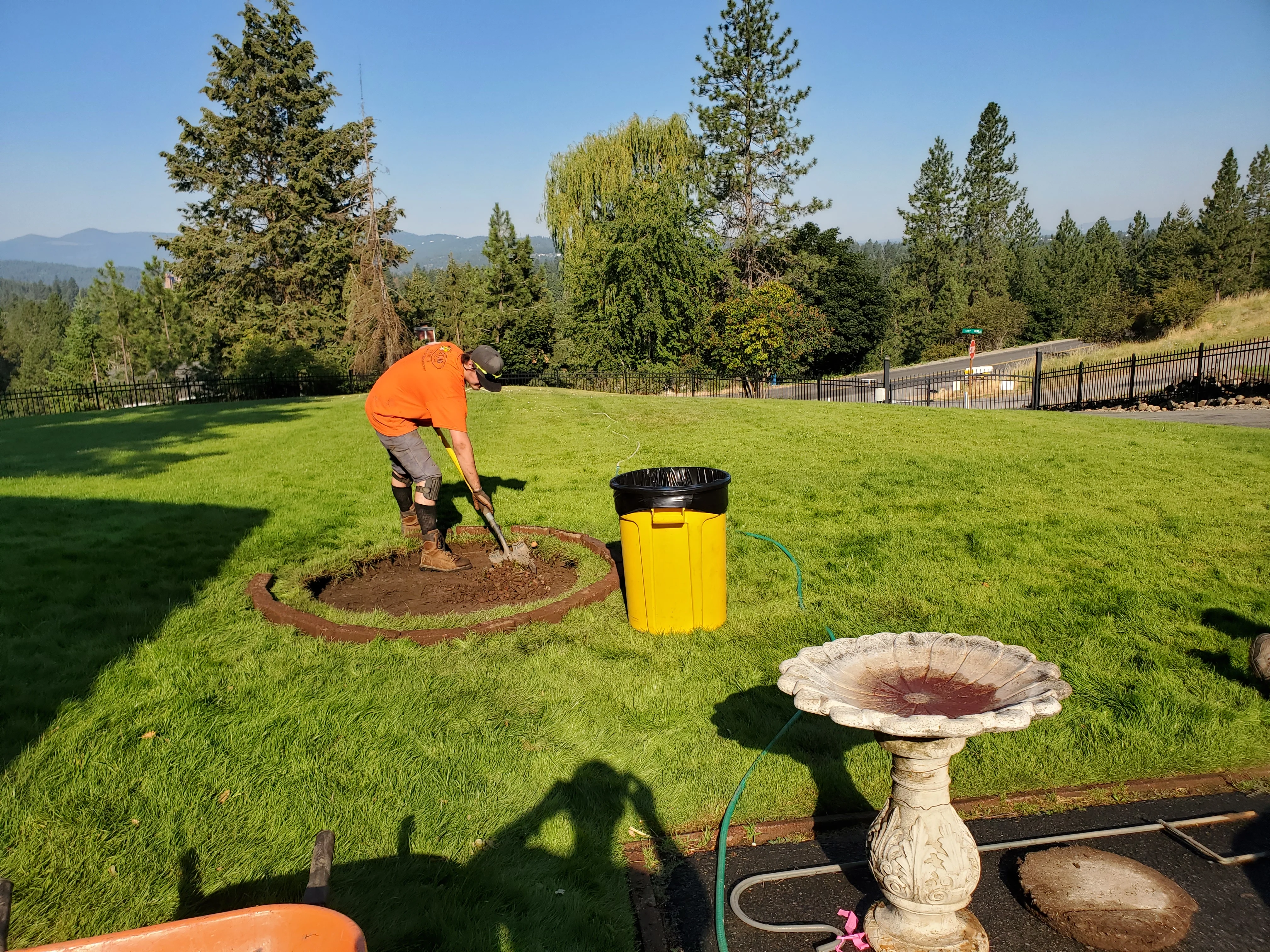 Landscaper installing mulch in newly edged garden bed with mountains visible in background