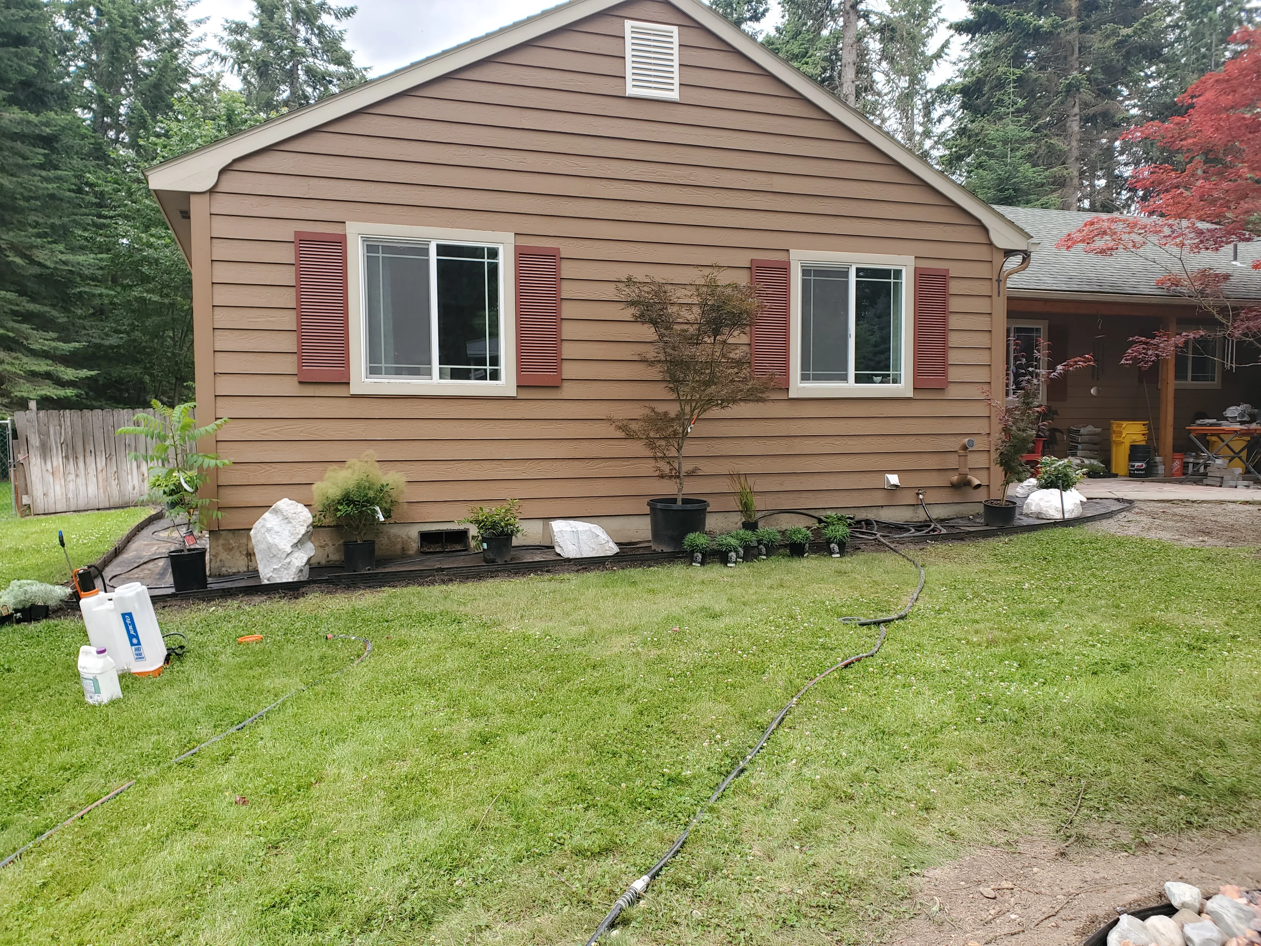 Brown siding home with new foundation landscaping, rock borders, and planted shrubs