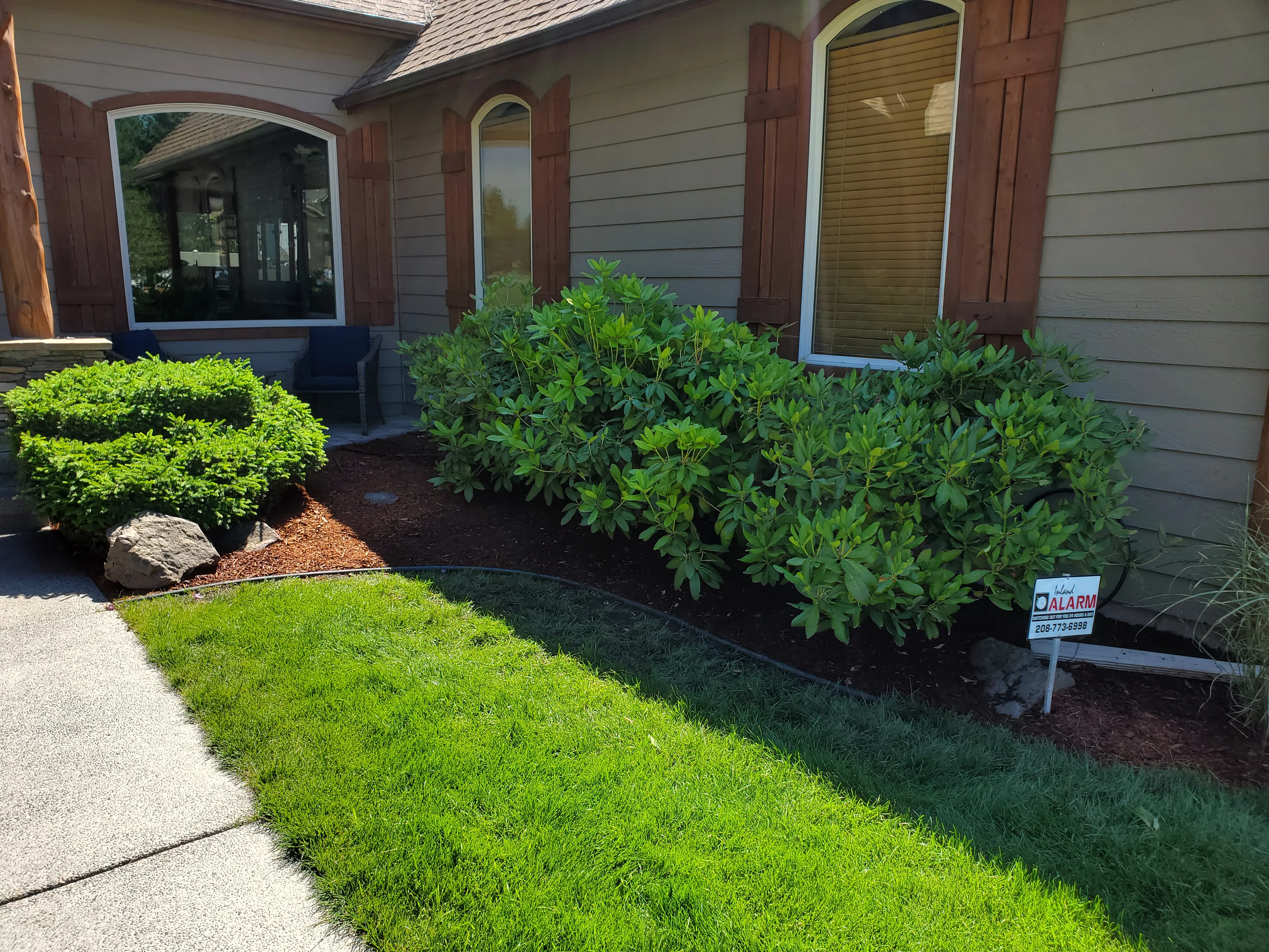 Front yard landscaping with mulch beds, green shrubs, and manicured lawn