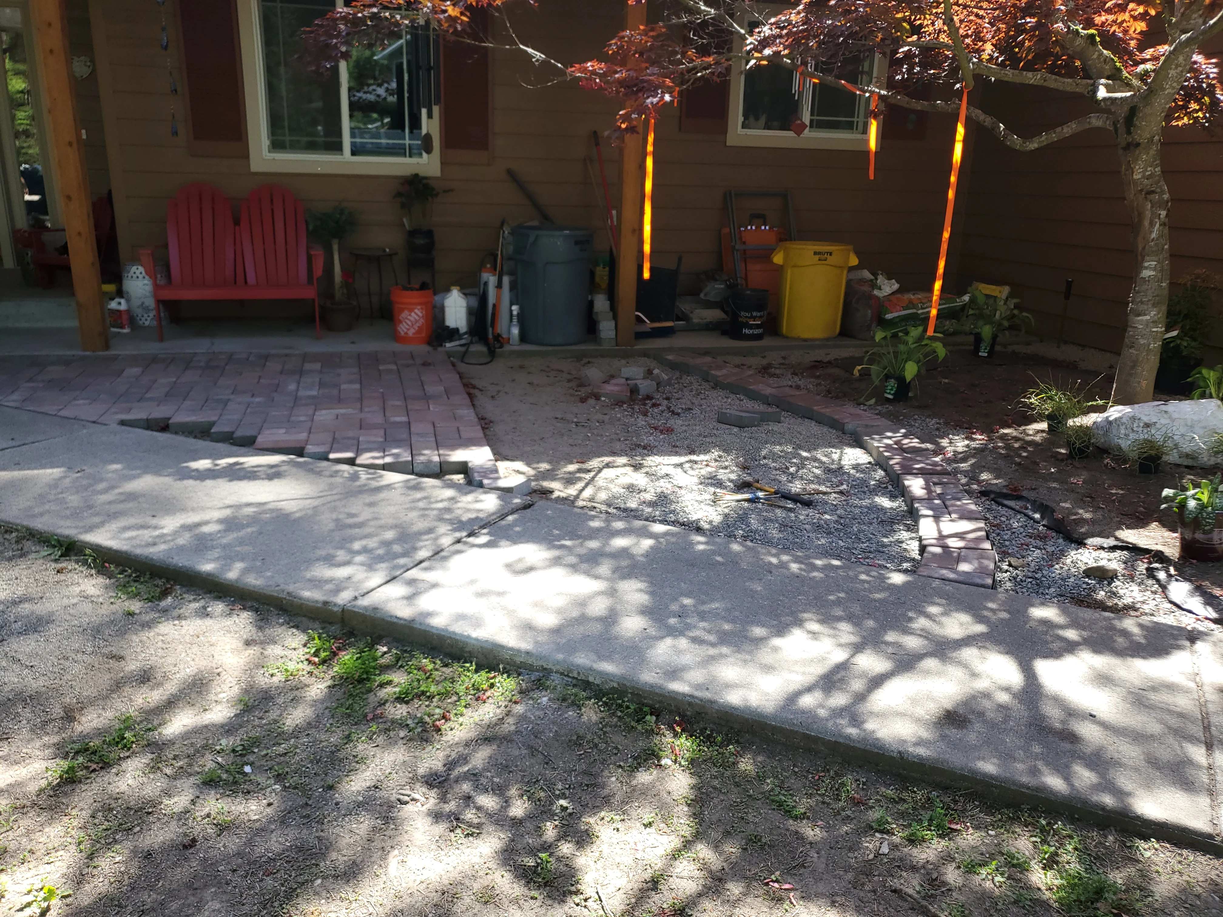 Newly installed concrete patio with decorative brick pavers and landscape edging in residential backyard