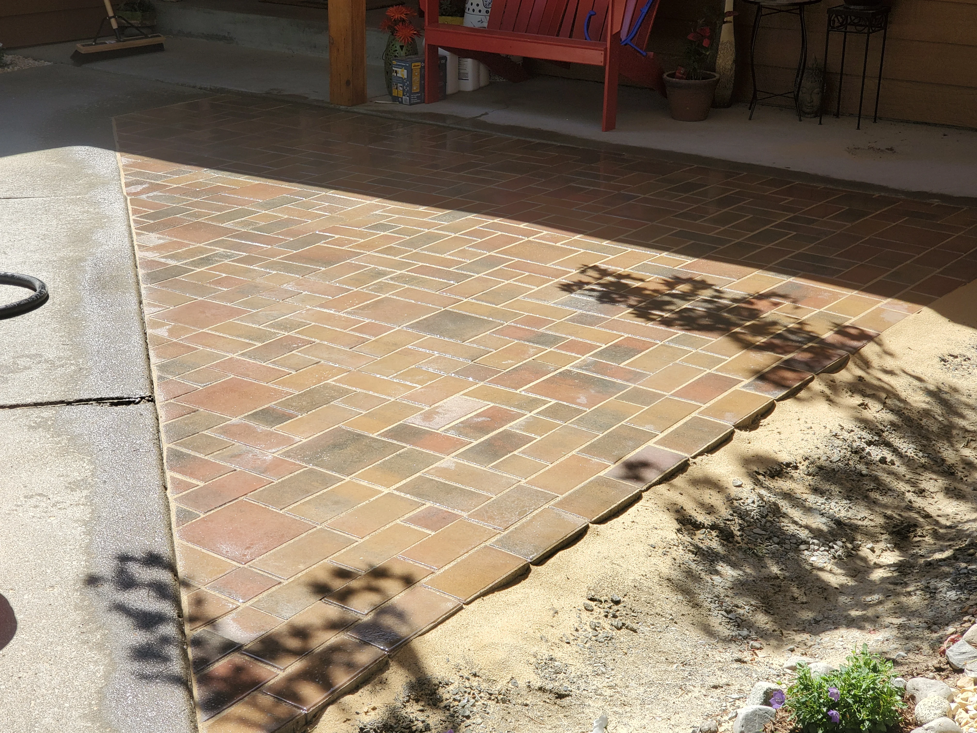 Terracotta brick patio with herringbone pattern and white grout lines in sunny backyard