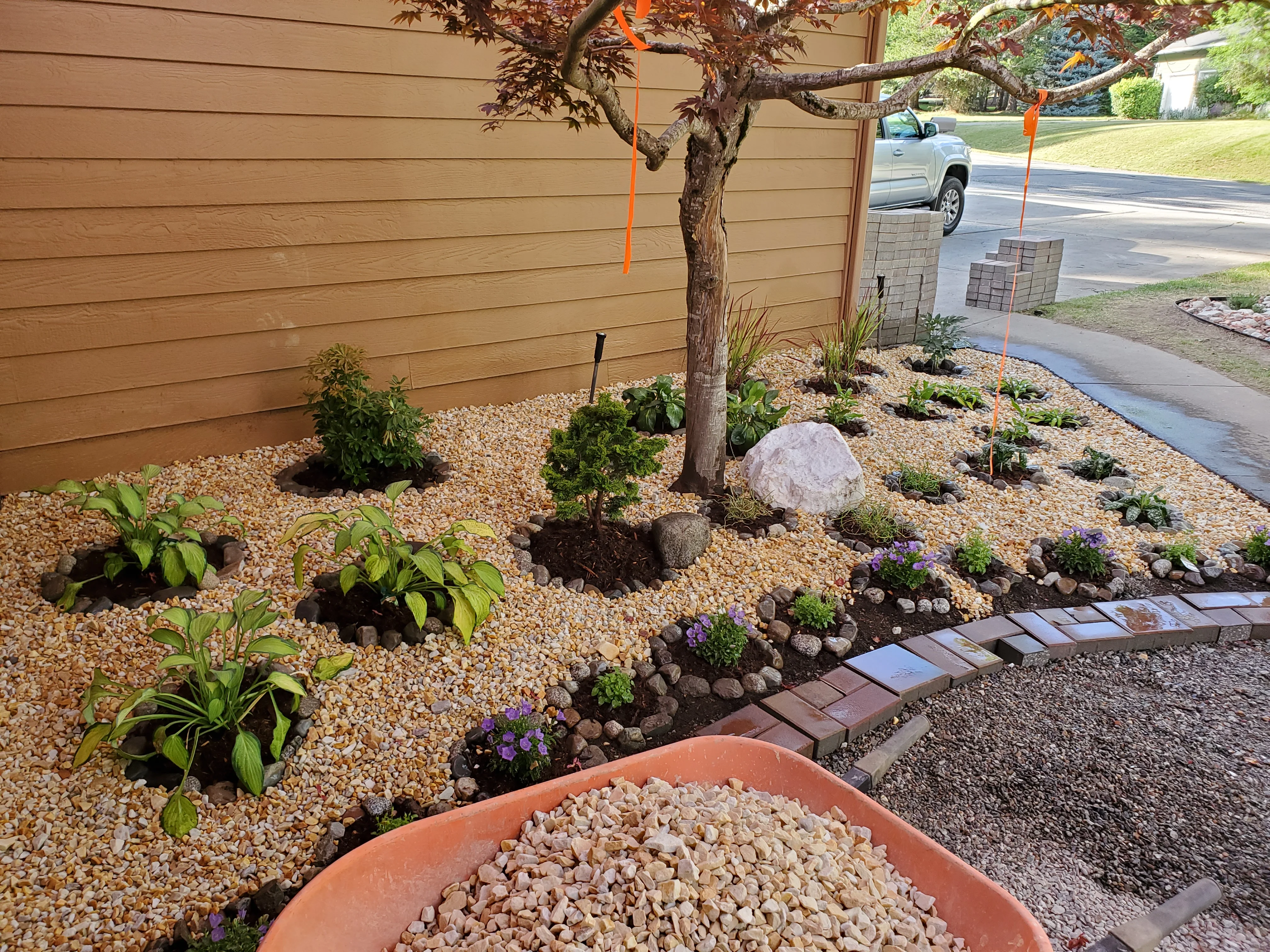 Xeriscape garden bed with river rock, native plants, and decorative stone borders