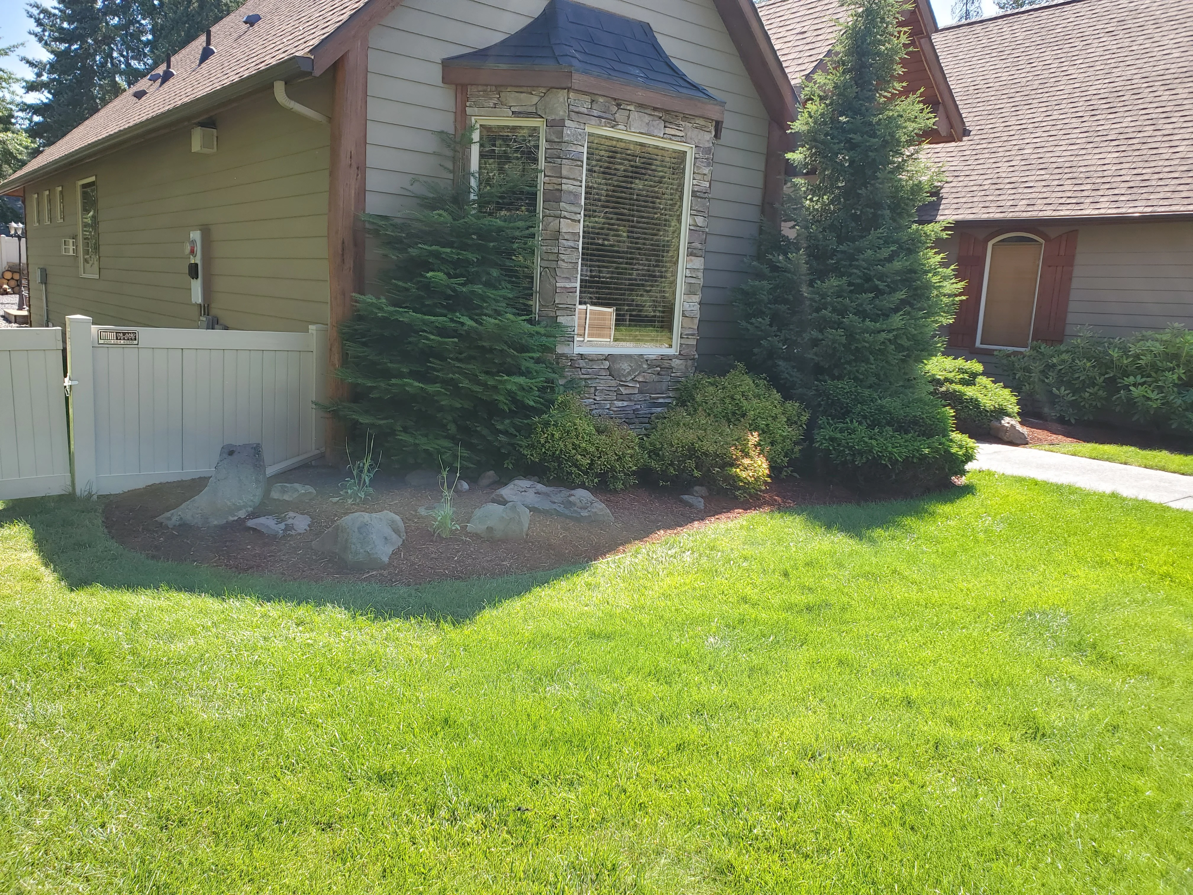 Front yard landscaping with mulch bed, boulders, and green shrubs