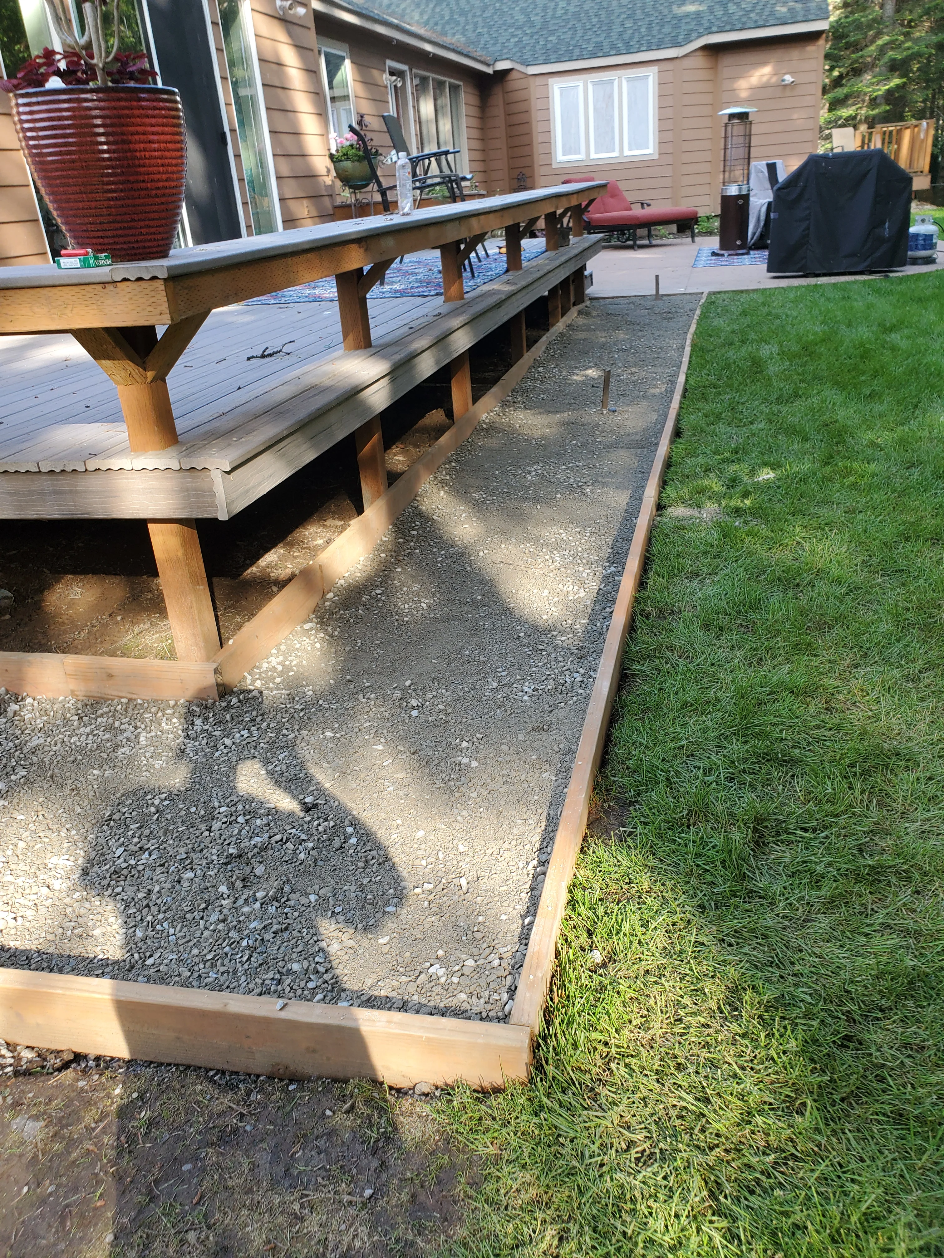 Gravel pathway with timber edging running alongside wooden deck and residential home