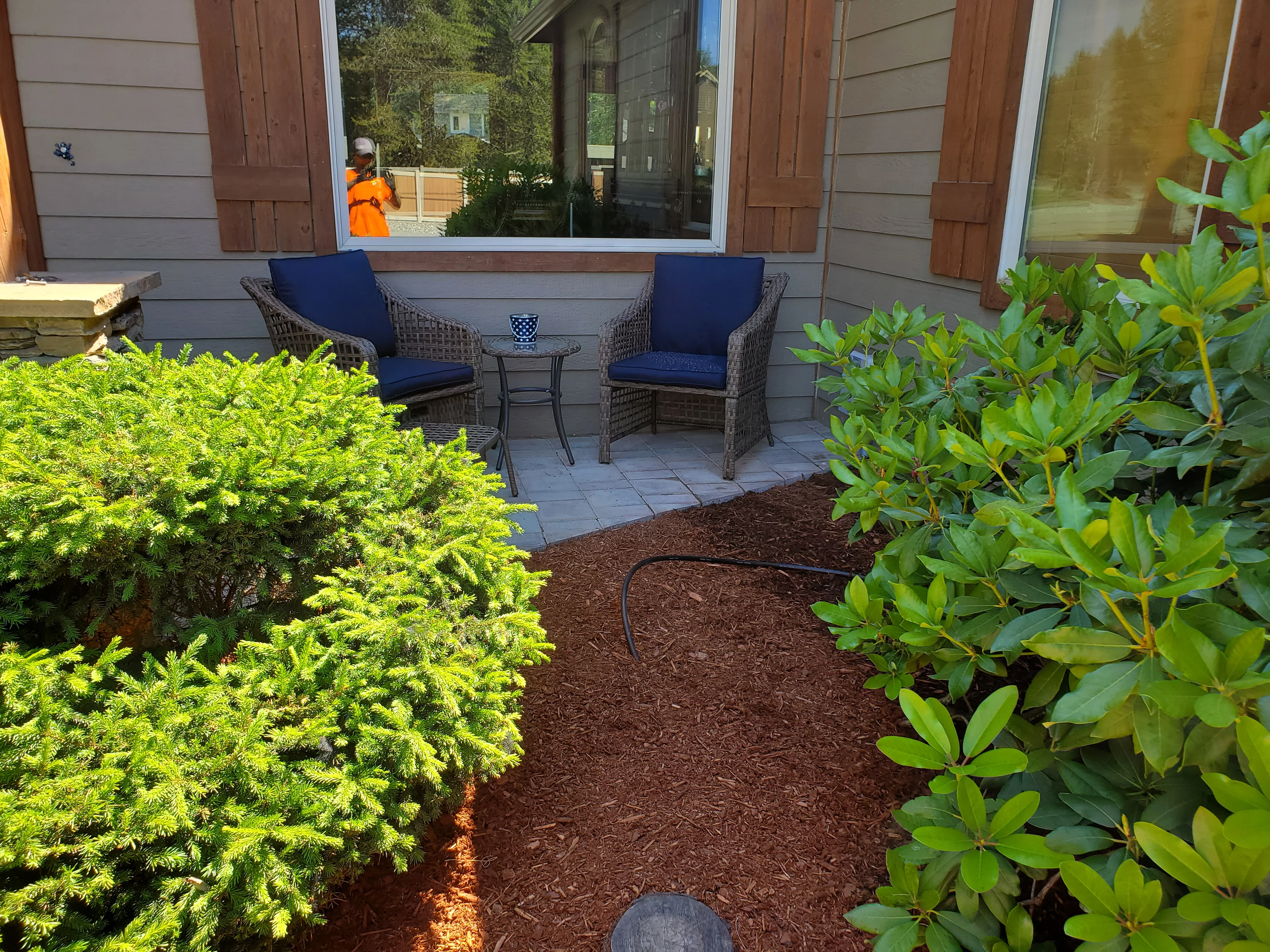 A finished paver patio installed in a Coeur d'Alene backyard, showing a level surface with clean edges and a seating area surrounded by a residential yard. The patio connects directly to the home's back door with no visible gaps or uneven joints.
