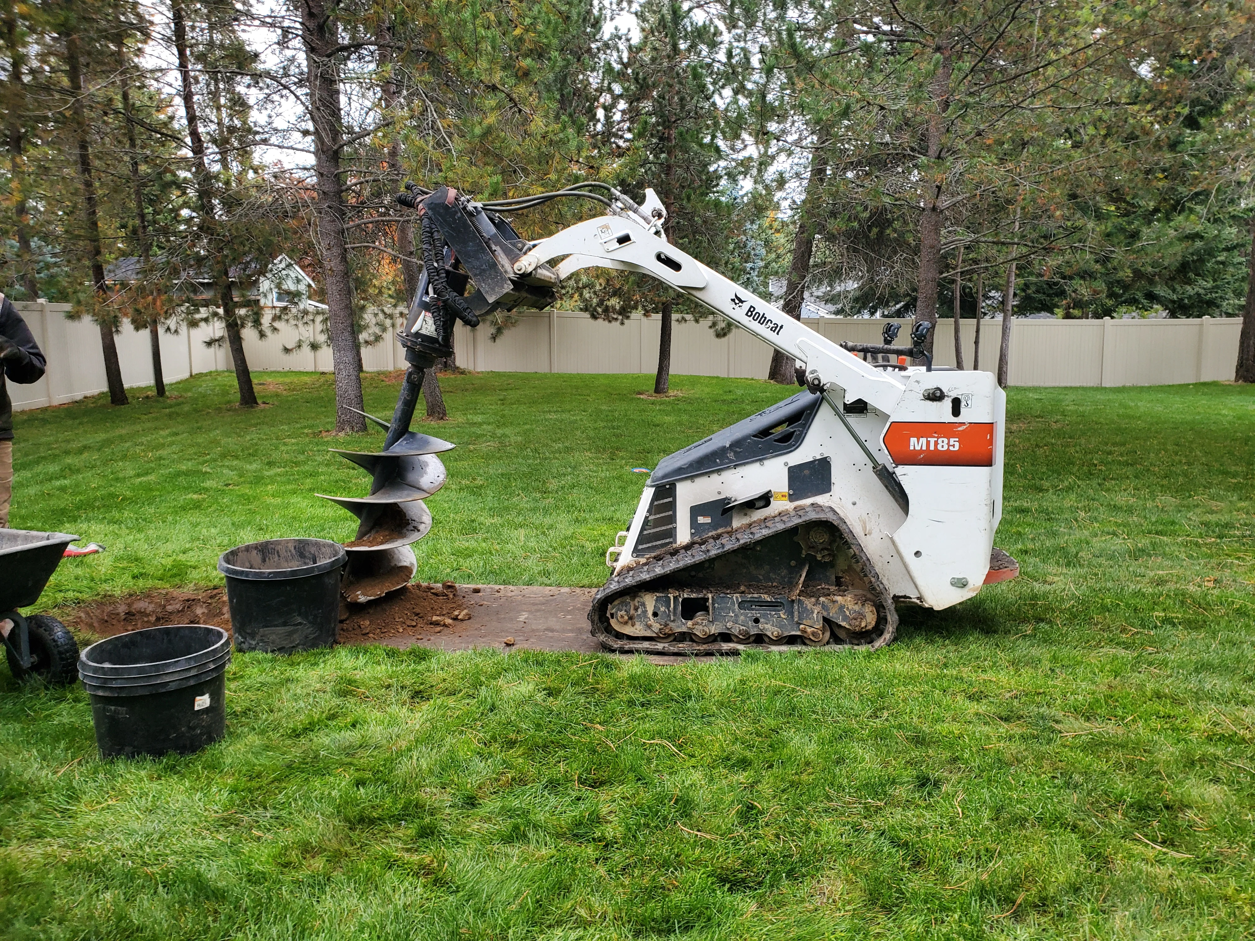 A freshly planted garden bed at a Coeur d'Alene residential property showing ornamental shrubs and perennials installed in prepared soil. The planting bed borders a lawn with North Idaho tree cover visible in the background.