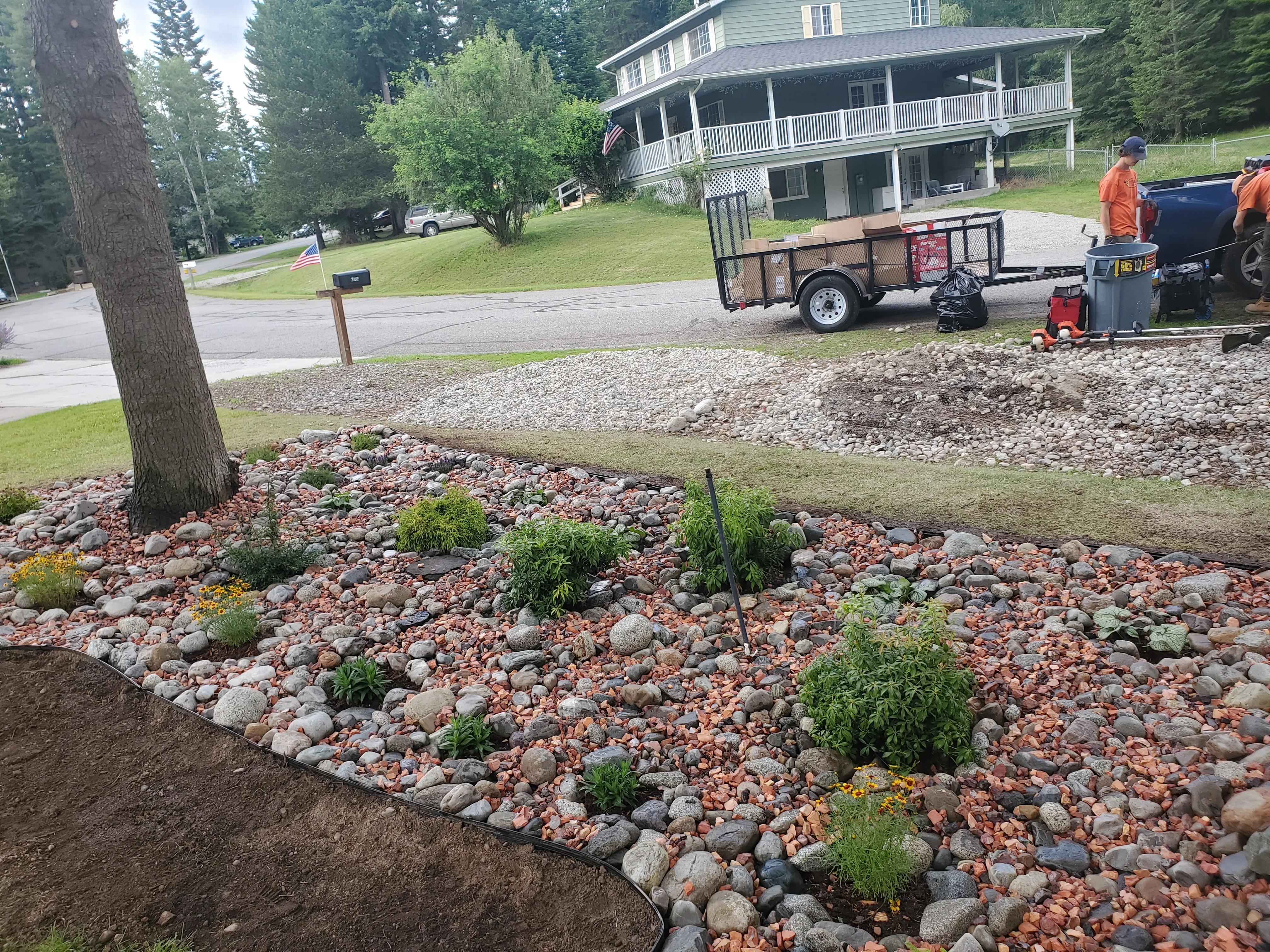 A fully cleared storage unit in Coeur d'Alene, Idaho after a professional cleanout, with an empty concrete floor and open roll-up door. A Bee Stung Yard Care LLC truck is loaded with removed furniture and boxes in the foreground.